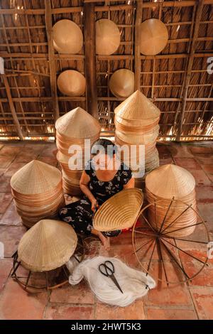 vecchia donna vietnamita che fa un cappello conico tradizionale a casa sua Foto Stock