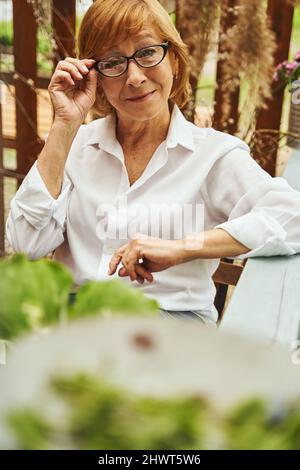 Felice signora matura rilassarsi tra natura sulla terrazza Foto Stock