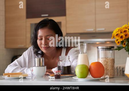 Giovane donna addormentata in attesa di occhi chiusi quando si fa caffè vietnamita gocciolamento a casa Foto Stock