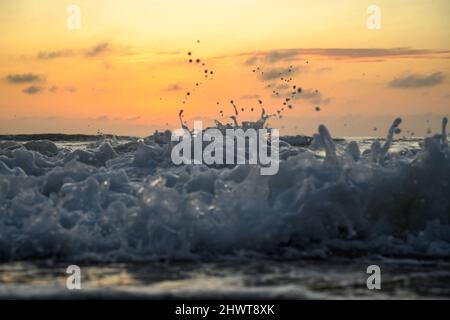 primo piano di onde che si infrangono su una spiaggia all'alba Foto Stock