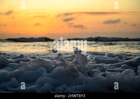 primo piano di onde che si infrangono su una spiaggia all'alba Foto Stock