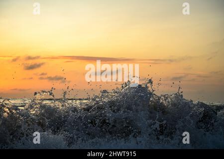 primo piano di onde che si infrangono su una spiaggia all'alba Foto Stock