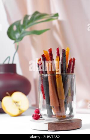 Rotoli colorati di frutta in pelle su un piatto su sfondo chiaro Foto Stock