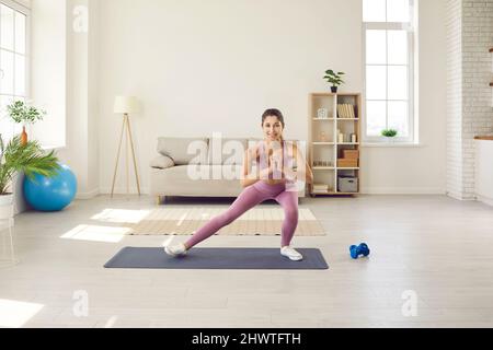 Allenatore di fitness femminile esegue esercizi sportivi di fronte alla webcam facendo streaming allenamento. Foto Stock