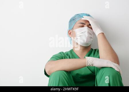 Stressato chirurgo disperato in maschera medica sofferenza dopo aver perso il paziente Foto Stock
