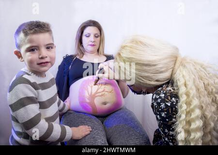 Donna incinta di otto mesi con figlio di tre anni. Verniciatura della carrozzeria Foto Stock