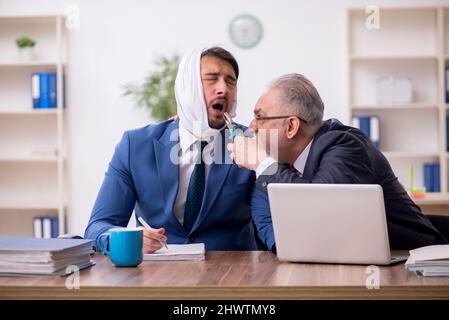 Giovane impiegato d'affari che soffre di mal di denti in ufficio Foto Stock