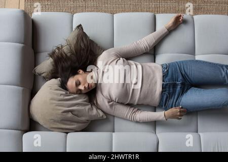 Sopra la vista donna stanca che dorme sul divano a casa Foto Stock