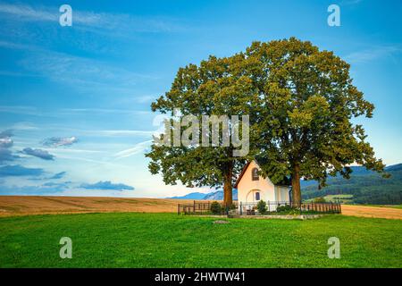 Paesaggio al tramonto con Cappella di San Rochus sopra il villaggio di Turie vicino Zilina città, Slovacchia, Europa. Foto Stock