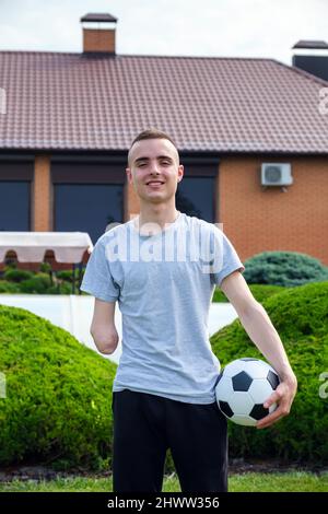 l'uomo con braccio amputato tiene il piede sulla palla di calcio mentre si alza sul prato Foto Stock