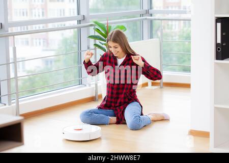 Donna accende l'aspirapolvere robot intelligente Foto Stock