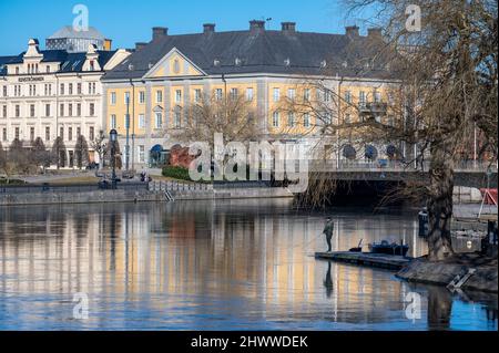 Uomo che pesca al fiume Motala a Norrkoping durante la primavera iniziale. Norrkoping è una storica città industriale svedese. Foto Stock