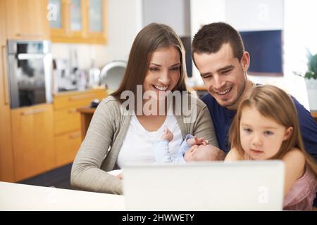 Incontra l'ultima aggiunta alla nostra famiglia.... Una giovane famiglia che passa del tempo insieme durante una chiamata online. Foto Stock