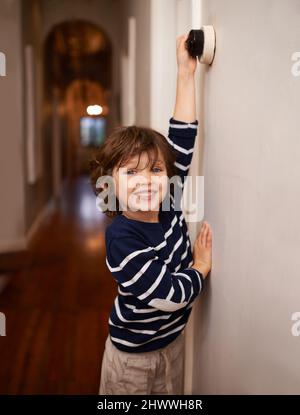 La conservazione ecologica inizia giovane. Un colpo corto di un ragazzino che spegne una luce in casa sua. Foto Stock