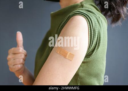 Vista ravvicinata del braccio della donna con bendaggio, immunizzazione vaccinata. Inoculazione, vaccinazione, concetto di paziente vaccinato. Foto Stock