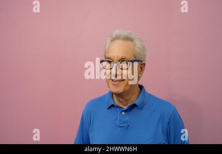 Bell'uomo vecchio in camicia blu su sfondo rosa Foto Stock
