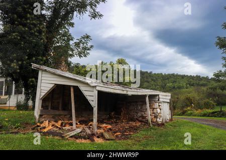 Un capannone di legno pendente mantiene il legno tritato asciutto in un giorno piovoso in una fattoria nelle colline della Virginia rurale. Foto Stock