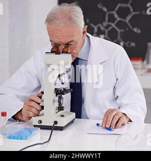 Scoperte rivoluzionarie in laboratorio. Scatto di uno scienziato maturo utilizzando un microscopio. Foto Stock