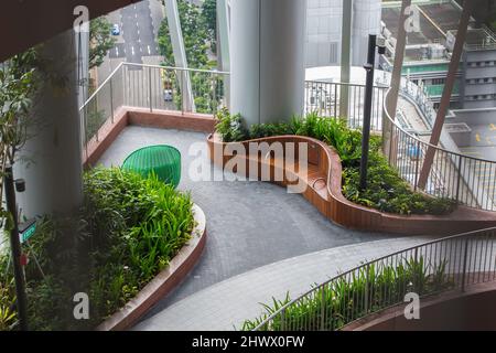 Uno spazio aperto per il pubblico dove riposare le gambe stanche all'Oasi Verde di CapitaSpring, alberi e piante piantati all'interno dell'edificio. Singapore. Foto Stock