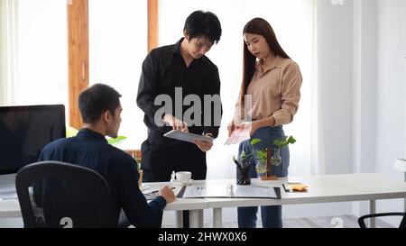 Il team dei designer d'interni lavora insieme in ufficio, lavorando al brainstorming e condividendo idee creative per il loro progetto. Foto Stock