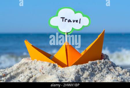 Orange Paper Boat su Sandy Seashore Close-up. Piccola barca da carta Foto Stock