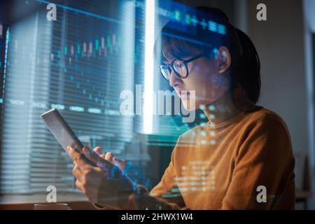 Giovane donna in occhiali che proietta il programma su tablet digitale durante il suo lavoro in ufficio Foto Stock
