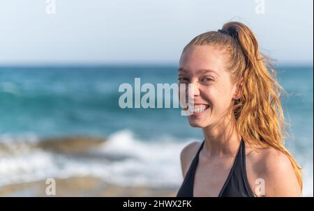 giovane donna che guarda la macchina fotografica sorridendo Foto Stock