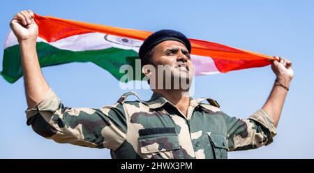 Esercito indiano soldato in mano che sventola bandiera indiana in uniforme - concetto di orgoglio nazionale, patriottismo, libertà e indipendenza Foto Stock