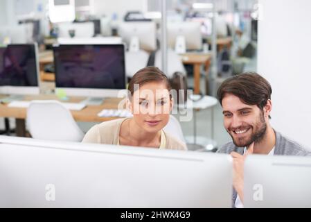 Orgoglioso del ruolo che ha svolto nel loro progetto. Scatto di un giovane uomo d'affari che mostra al suo collega qualcosa sul computer. Foto Stock