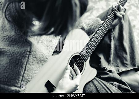 Fotografia in bianco e nero. Ragazza suona la chitarra. Primo piano verticale dall'alto. Stile retrò. Monocromatico. Foto Stock