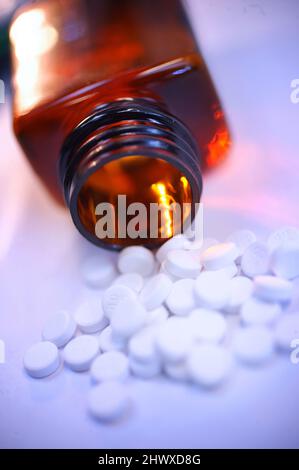 Compresse bianche fuoriuscita da una bottiglia di medicina Foto Stock