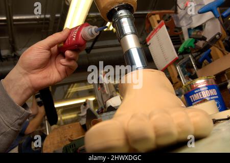 Un tecnico che costruisce una gamba protesica in un'officina di protesi Foto Stock