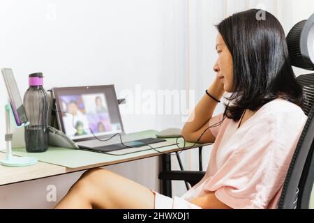 Donna d'affari che effettua una videochiamata mentre si riunisce con i colleghi su un portatile. Foto Stock