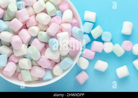 Marshmallows colorati in una ciotola su sfondo blu Foto Stock