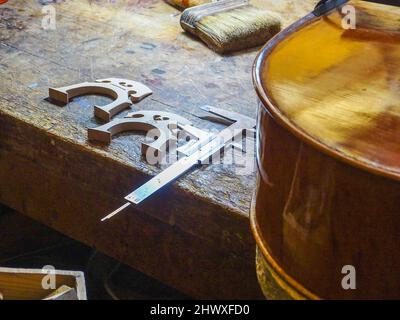 Carlos Roberts maestro liutaio violino creatore scegliere il ponte giusto per un nuovo violoncello della sua produzione presso la sua officina Foto Stock