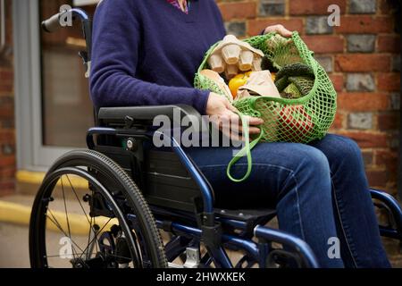 Primo piano della donna in Wheelchair Holding Zero Waste Packaging Shopping in Sustainable Bag Foto Stock