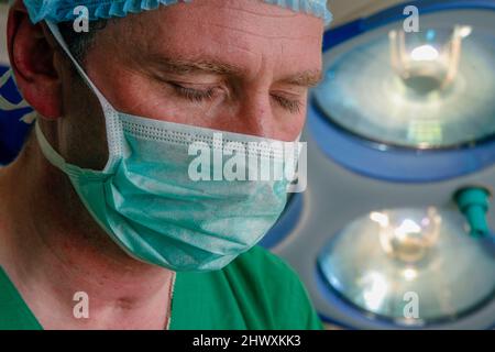 Un chirurgo mascherato dorme senza una lampada chirurgica in una sala operatoria. (MODELLO RILASCIATO) Foto Stock