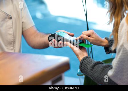 Donna che immette il codice della carta bancaria sulla macchina da swiping in clinica Foto Stock