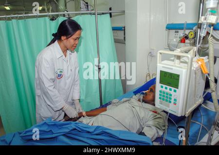 Questo paziente riceve liquidi endovenosi (iv) (nel braccio destro) e ossigeno tramite una cannula nasale. Indossa un ossimetro a impulsi sul suo indice fi destro Foto Stock