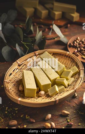 Cubetti di cioccolato bianco con pistacchi su piatto di bambù, natura morta Foto Stock