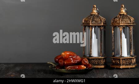 Lanterna di fuoco selezionata e date su tavola di legno. Concetto di festa di Ramadan kareem, spazio di copia per il testo. Focus su frutta datteri Foto Stock