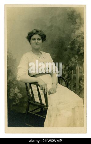 Cartolina originale pre-WW1 era di sicuro-guardando bella donna, ragazza anziana, prospera classe media o superiore, seduto, in un abito estivo bianco, datata 1913 luglio sul retro, Regno Unito Foto Stock