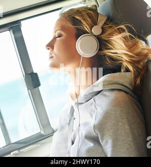 Lasciandole andare via le sue cure.... Colpo di donna in un'auto che riposa gli occhi mentre il vento soffia attraverso i suoi capelli e lei ascolta la musica. Foto Stock