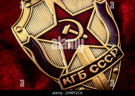 Servizio segreto, agenzia di intelligence e concetto di spionaggio con macro primo piano su un badge KGB era guerra fredda dall'ex URSS su sfondo rosso Foto Stock