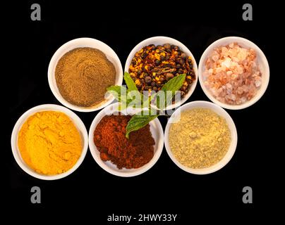 Vivacizzare qualsiasi piatto. Shot di un assortimento di spezie colorate su sfondo nero. Foto Stock