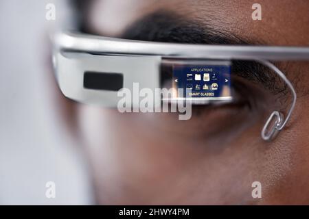 Uno sguardo più da vicino. Primo piano di un giovane uomo utilizzando smartglass per navigare in rete. Foto Stock