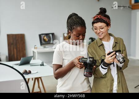 Vita in alto ritratto di due fotografi femmina con le fotocamere mentre si lavora in studio fotografico, spazio copia Foto Stock