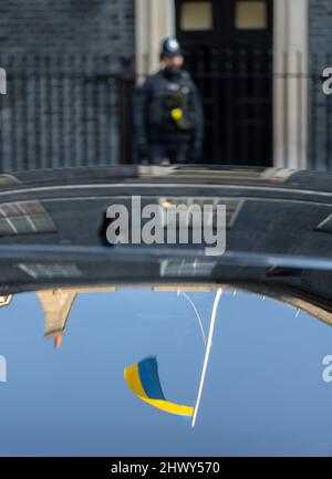 8 marzo 2022, Londra, Regno Unito. La bandiera Ucraina si è riflessa sul lunotto di un'automobile ministeriale durante la riunione settimanale del gabinetto a 10 Downing Street, Londra, con un ufficiale di polizia sullo sfondo Foto Stock