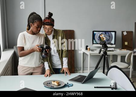 Ritratto di due fotografi femminili che guardano le foto in fotocamera mentre lavorano in studio fotografico, spazio di copia Foto Stock