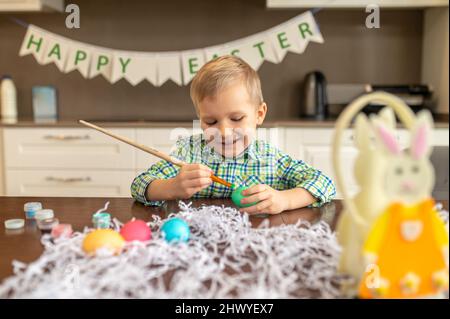 Sorridente felice concentrato bambino preparazione per Pasqua Foto Stock